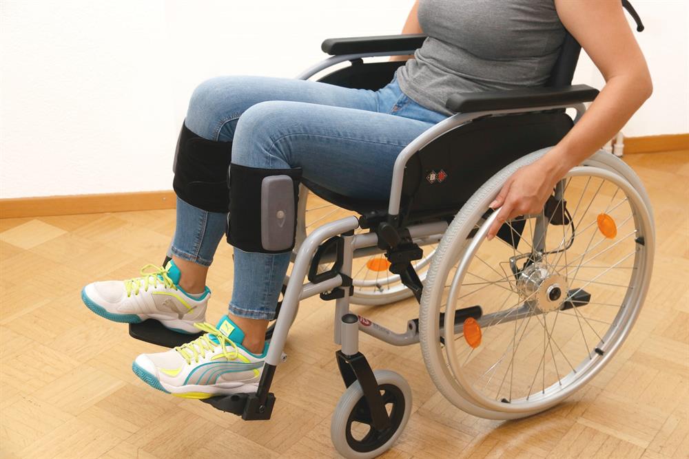 Legfit relax Kompressionsmassage, schwarze Manschette mit Steuergerat am Unterschenkel einer Rollstuhlnutzerin