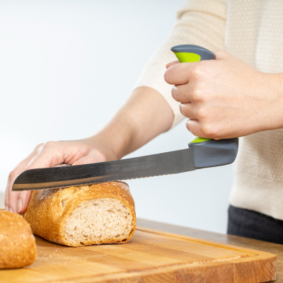 Brotmesser mit Bügelgriff schneidet Brot auf einem Holzbrett (Symbolbild)