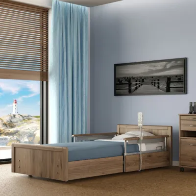 Pflegebett Sentida sc in Holzdekor, niedrig im hellen Zimmer mit blauer Matratze und Seitengittern (Symbolbild)