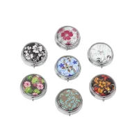 Sieben runde Pillendosen aus Metall mit Druckknopf-Deckel und verschiedenen floralen Mustern